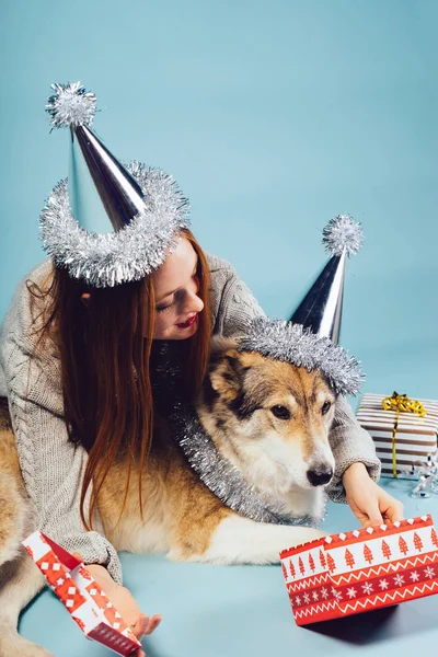 Red-haired 女孩拥抱她的狗, 在节日帽, 新年的气氛 — 图库照片