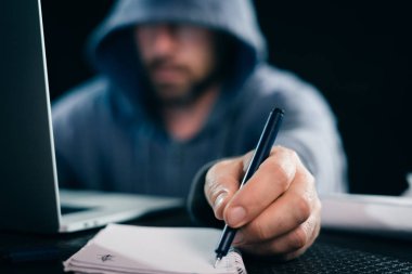 Not defterinizdeki notlar yapıyor dizüstü arkasında oturan genç hacker