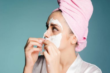 Kız gri bir arka plan üzerinde cilt temizlemeye maskesini çıkarır