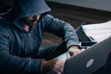 Bir hacker bir kapüşonlu sweatshirt ' bir dizüstü oturur
