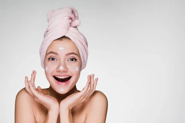 Ung flicka med en handduk på hennes huvud skrattande pålagt med ansiktsmask — Stockfoto
