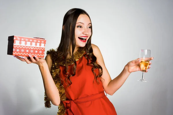 Девушка с бокалом шампанского празднует Новый год с подарком в руках — стоковое фото