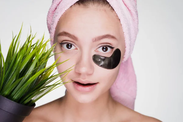 Flicka med en handduk på huvudet sätter på ansiktsmask — Stockfoto