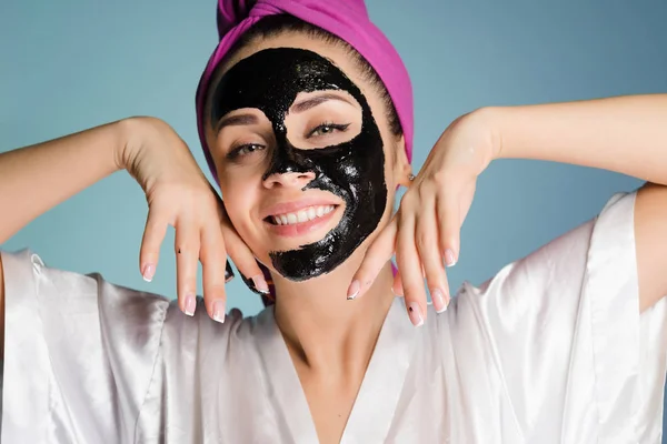 Молодая девушка с полотенцем на голове надевает маску для лица — стоковое фото