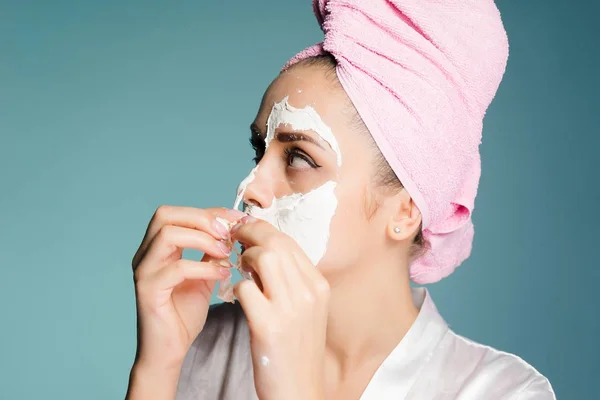 Fille sur un fond gris enlève le masque pour nettoyer la peau — Photo