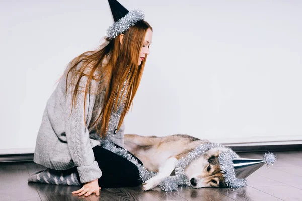 Ein Mädchen mit festlichem Hut sitzt neben einem großen Hund — Stockfoto