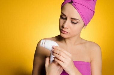 Kız başında bir havlu ile sorun cilt temizliği için aygıt inceliyor