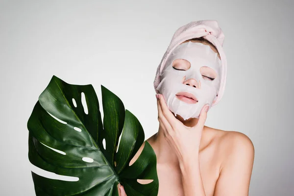 Chica después de la ducha con una toalla en la cabeza se aplica una mascarilla —  Fotos de Stock