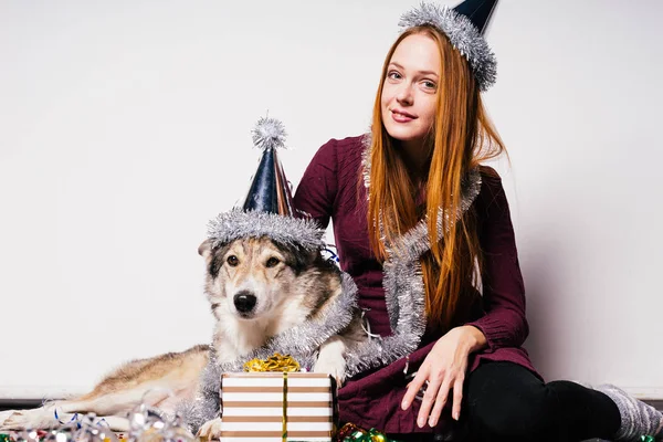 La fille dans une casquette festive se trouve à côté du chien — Photo