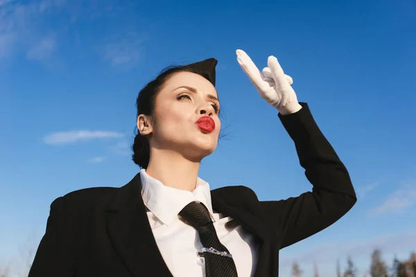 Letuška legrační atraktivní žena v uniformě proti modré obloze — Stock fotografie