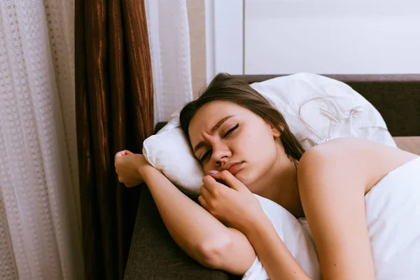 Trauriges junges Mädchen liegt im Bett, wacht frühmorgens auf und will nicht aufstehen — Stockfoto