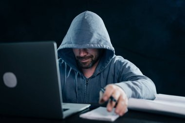 yüzünü başlık altında sırıtan gizemli adam hacker gizler
