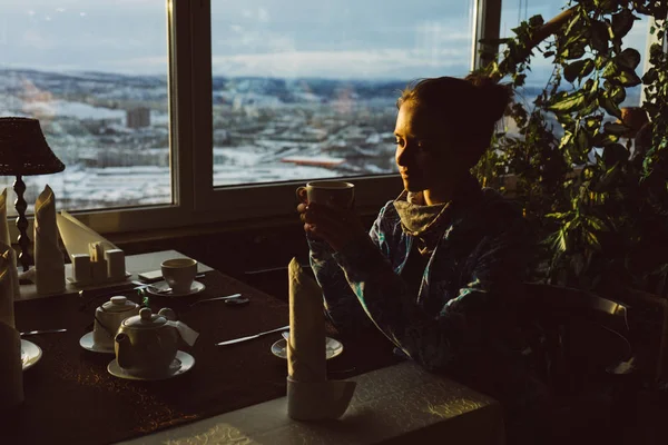 Una giovane ragazza si siede in un caffè, beve un delizioso tè, si gode il sole e si rilassa — Foto Stock
