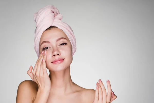 Attraktive junge Mädchen mit rosa Handtuch auf dem Kopf Anwendung Feuchtigkeitscreme auf das Gesicht — Stockfoto