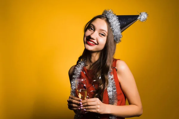 Bela menina sorridente com batom vermelho, em um boné celebra o ano novo 2018, segura uma taça de champanhe — Fotografia de Stock