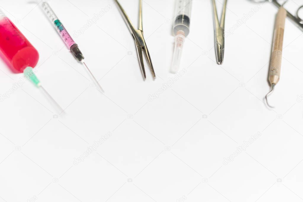 on a white surface are medical dental instruments and syringes of different sizes