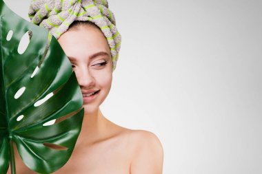 Kafasındaki bir havlu ile güzel kız gülümseyerek tutan bir büyük yeşil yaprak, gün spa