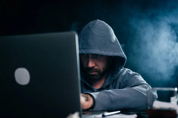 Misterioso homem perigoso no capô fazendo algo ilegal no laptop — Fotografia de Stock