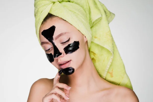 Μια ελκυστική νεαρή κοπέλα θέλει ένα καθαρό δέρμα στο πρόσωπό της, εφαρμόζεται ένα μαύρο καθαρισμού μάσκα στο πρόσωπό της — Φωτογραφία Αρχείου