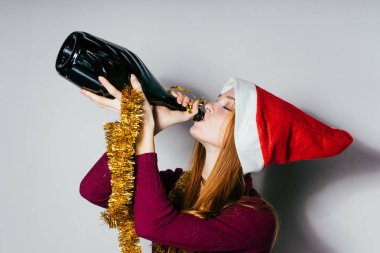 Kızıl saçlı genç kız kırmızı bere içinde yeni yıl, bir şişe içki şampanya kutluyor