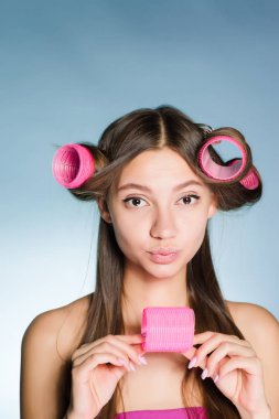 güzel genç kız üzerinde kafa onun büyük pembe curlers iyi bakmak istiyor