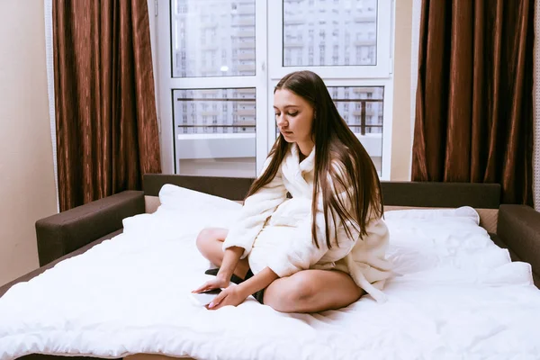 Triste joven con un vestido de terciopelo blanco se sienta en una cama sola — Foto de Stock