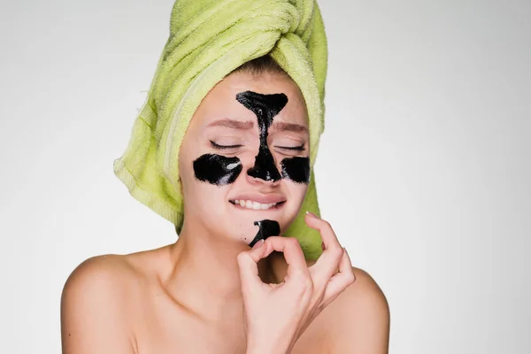 La joven ha puesto o rendido una máscara de limpieza negra en la cara, se la quita con un dolor — Foto de Stock