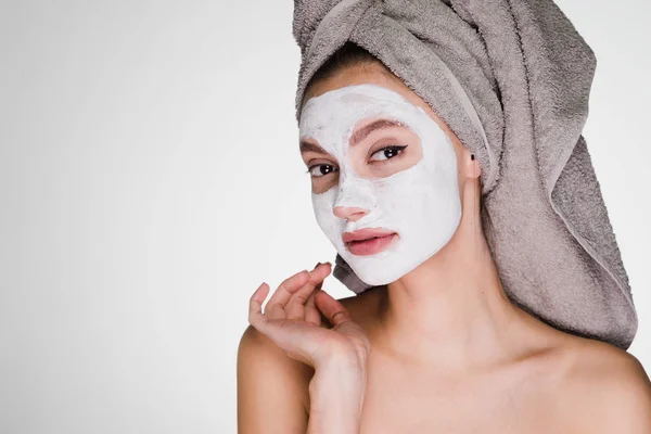 Привлекательная девушка с полотенцем на голове хочет чистую кожу на лице, нанес белую питательную маску — стоковое фото