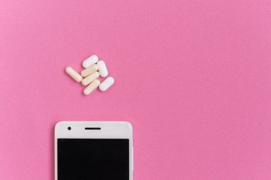 pembe bir yüzey üzerinde beyaz bir akıllı telefon ve tabletler olduğunu