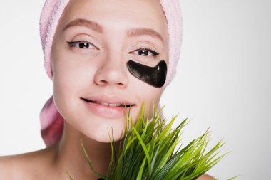 Kafasındaki bir pembe havlu ile güzel çekici kız bir yeşil çim siyah bir yama göz altında ellerini tutar