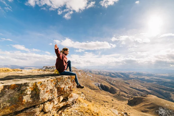 Active young girl leads a healthy lifestyle, sits on the edge of the mountain and enjoys the sun and nature — Stock Photo, Image