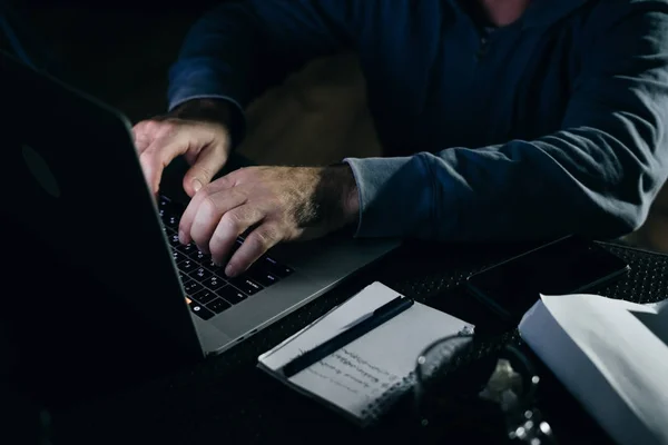 A mysterious man hacks something on a laptop in the dark — Stock Photo, Image