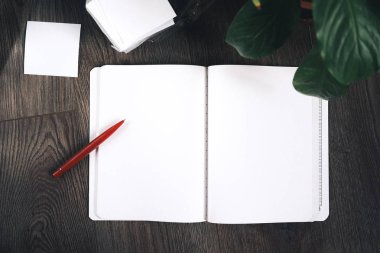 Beyaz defter kalem ile ahşap bir masaya yatıyor