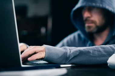 genç adam hacker bir kukuleta ile bir kazak'ı bir dizüstü oturur