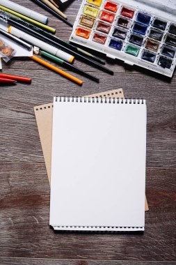Ahşap bir masa üzerinde çok renkli boyalar yalan arka plan üzerinde beyaz kağıdın
