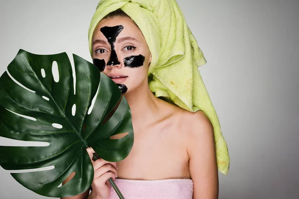 Jovencita con una toalla en la cabeza y con una máscara limpiadora en la cara — Foto de Stock