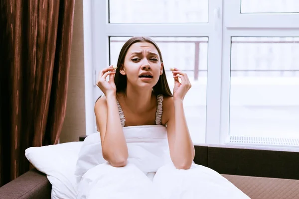 Расстроена девушка сидит на кровати после утреннего пробуждения — стоковое фото