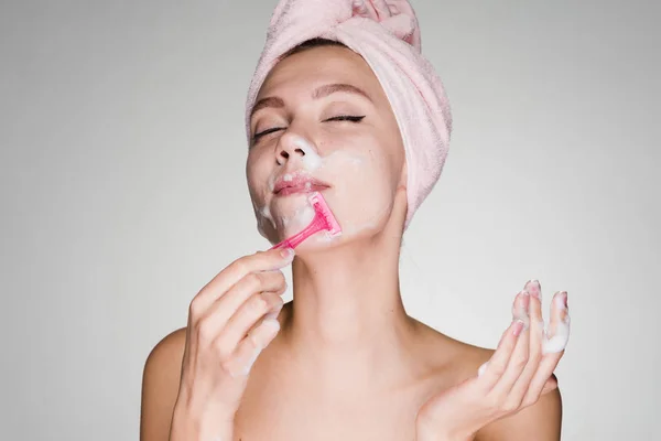 Menina feliz com uma toalha na cabeça fazendo uma depilação em seu rosto — Fotografia de Stock