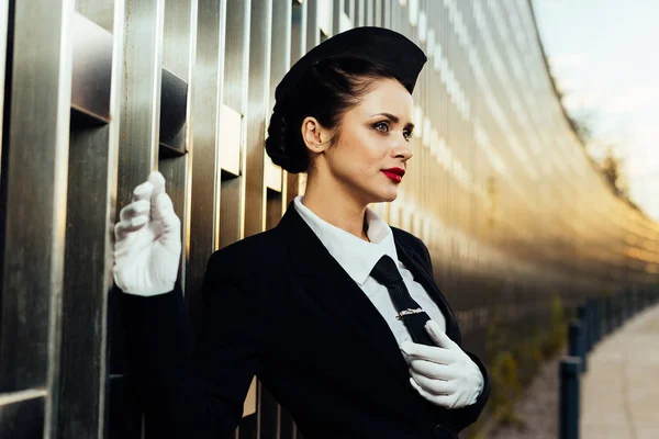Молода дівчина стюардеса в білих рукавичках на фоні будівлі — стокове фото