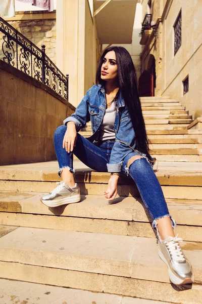 Stylish young girl with long hair sitting on the stairs — Stock Photo, Image