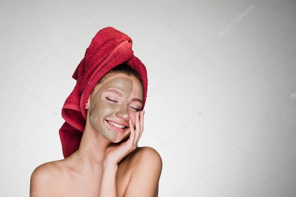 A young girl with a towel on her head applied a mask to cleanse the skin of her face