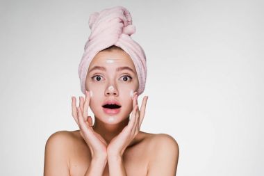 güzel kızın yüzüne karşı nemlendirici uygulayarak başında pembe havlu ile şaşırttı