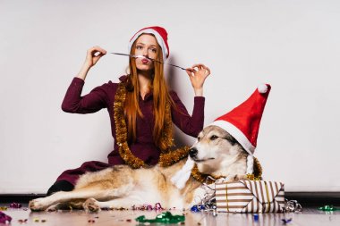 Onu köpek, hediyeler ve gümüş gelin teli, Noel Baba'nın Noel Baba gibi kırmızı kapaklar ile yeni yıl kutlama mutlu gülümseyen Kızıl saçlı kız