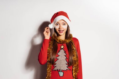 sevimli genç kız kafasına 2018, yeni yıl için Noel Baba gibi kırmızı bere gözleri yamalar altında bekliyor