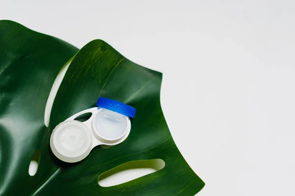 На большом зеленом листе лежит пакет для контактных линз — стоковое фото