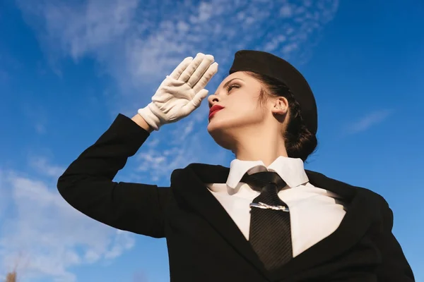 Confiant belle femme hôtesse de l'air en uniforme attendant son vol sous le ciel bleu Photo De Stock