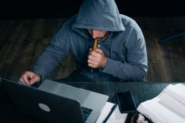 gizemli adam hacker, yüzünü başlık altında gizler ve bir nargile içiyor