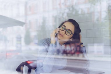 bir kafede, gözleri kapalı, telefonda konuşurken dalgın genç kız düşünüyor