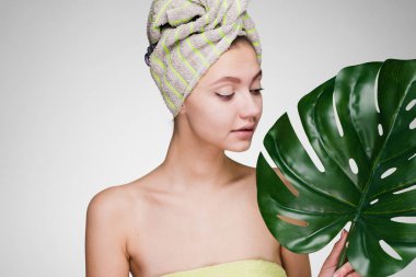 sevimli genç kız başında bir havlu ile yaprak yeşil elinde tutar.
