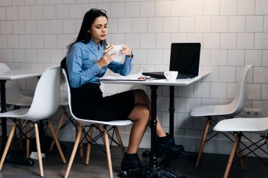 meşgul genç esmer kız öğrenci dizüstü yakınındaki kafede öğle yemeği mavi gömlekli
